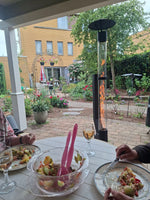 Sällskap äter under en veranda medan en pelletskamin brinner i trädgården