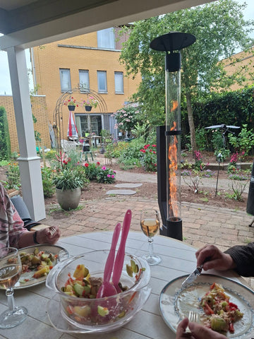 Sällskap äter under en veranda medan en pelletskamin brinner i trädgården